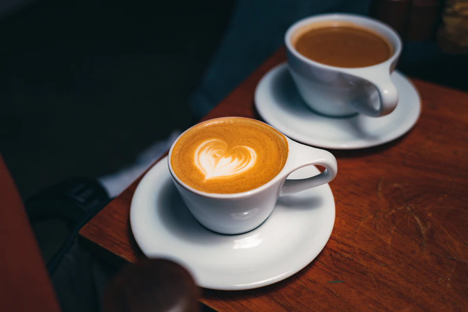 Duas chávenas de café em cima de uma mesa de madeira